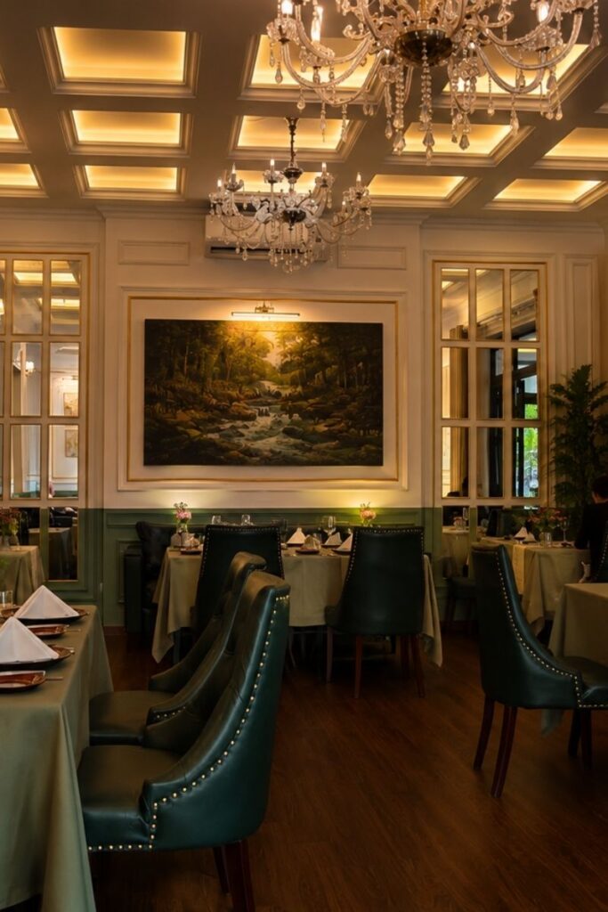luxurious chandelier-lit dining room with teal chairs and coffered ceiling at The Temptation French Restaurant